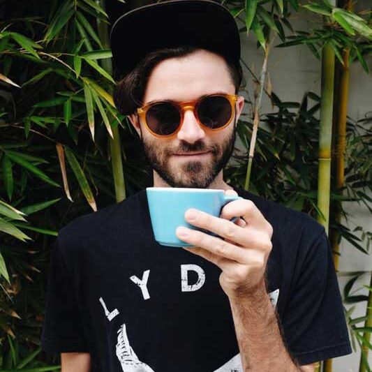 man wearing sunglasses holding blue coffee cup small