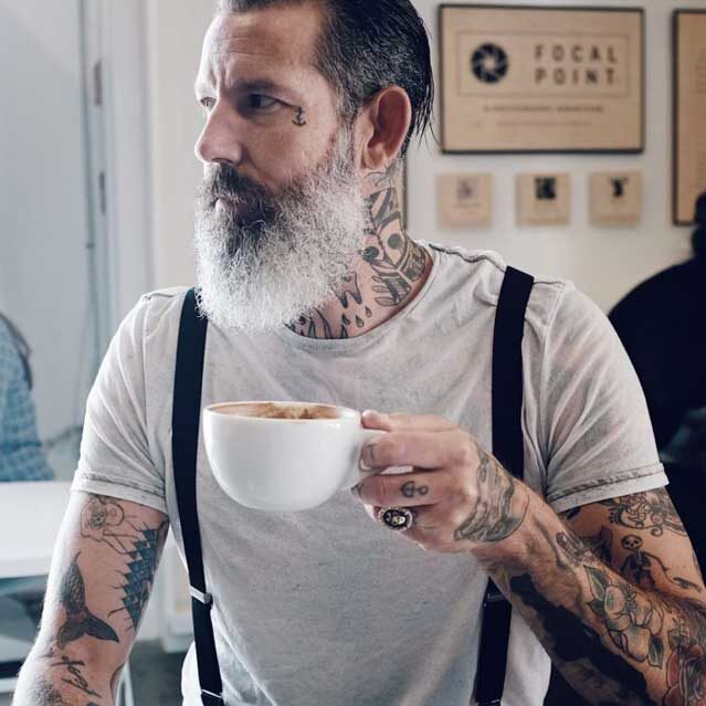 tattooed man holding coffee cup small